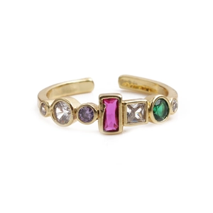 Détail macro d'une bague dorée montrant des pierres zircons multicolores et anneau réglable