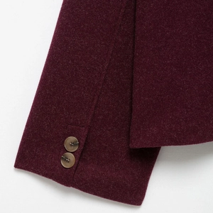 Detail of wine red wool jacket sleeve featuring brown marbled buttons and fabric texture