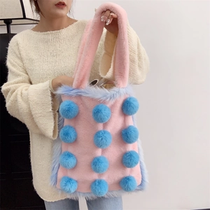 Nahaufnahme einer rosa Plüschtasche mit blauen Fellbommeln und weichem Kunstfellbesatz