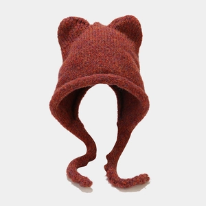 Detail of reddish-brown knit hat with cat ears and braided straps for winter warmth