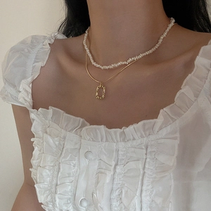Detail of layered freshwater pearl necklace and gold rectangular pendant on model