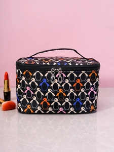 Detail of square makeup bag with penguin print, dual zippers, and top handle on marble surface