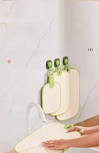 Three-piece beige and green cutting board set with wall hooks for kitchen organization