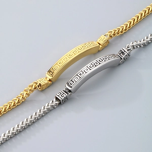 Detail of gold and silver stainless steel dragon bone bracelets with Greek key pattern