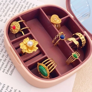 Pink jewelry box with assorted vintage gold gemstone rings and pearl settings on paper