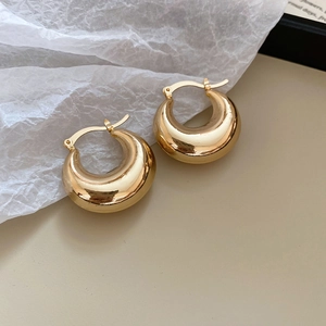 Detailed close-up of chunky gold hoop earrings with a high-polished mirror finish