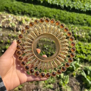 Detailed view of large gold cutout metal wall decor with amber stones held in nature