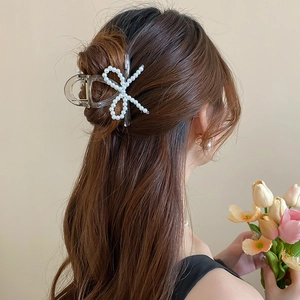 Detail of clear acrylic hair claw clip with white faux pearls on elegant long brown hair