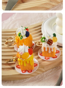Detailaufnahme der Mini-3D-Kuchen-Schlüsselanhänger mit Früchten und Sahneverzierung