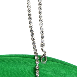 Close-up of sparkling rhinestone chain strap with metal clasp on green dress fabric