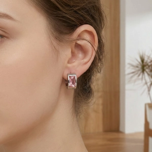 Close-up of pink emerald-cut gemstone huggie earrings in silver-toned finish worn by a model