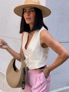 Gilet femme ajusté sans manches beige porté avec un pantalon rose et des accessoires