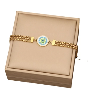 Golden multi-layer evil eye bracelet with blue enamel and sparkling crystals on jewelry box