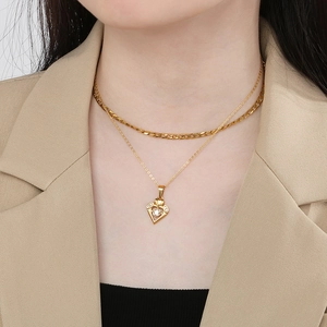 Detailed view of gold double-layer necklace with hollow heart pendant and inset crystal