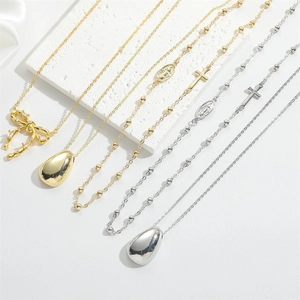 Detailed view of layered 14K gold and silver necklaces with cross and bow charms