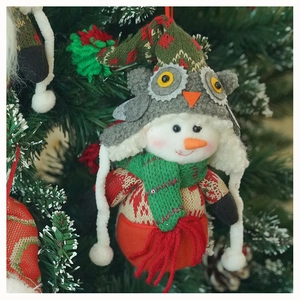 Detailed plush snowman ornament with owl knit hat hanging on a festive Christmas tree