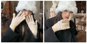 Detail of beige knitted touchscreen glove with small white tag and soft knit texture