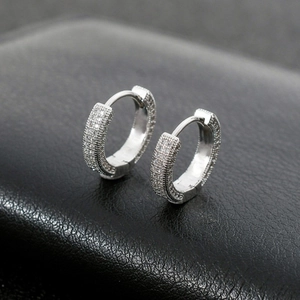 Macro shot of silver huggie hoop earrings with micro-paved zircons on black leather
