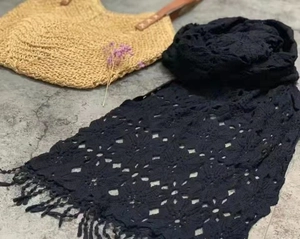 Detailed view of black crochet knit scarf with delicate embroidery and fringe tassels