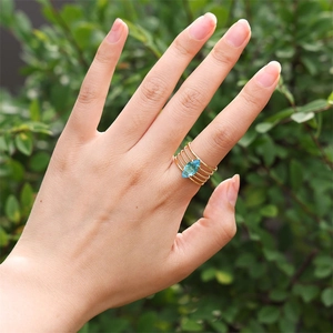 Dettaglio anello dorato multistrato con gemma blu taglio marquise sulla mano