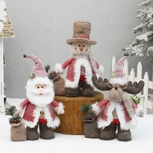 Three Christmas plush dolls including Santa and snowman on wooden stumps for decor