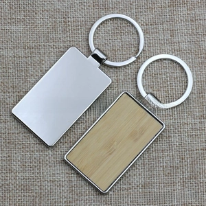 Detail of rectangular bamboo wood and metal keychains displayed on a rustic burlap background