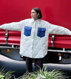 Dettaglio cappotto trapuntato bianco con tasche a contrasto blu e colletto a camicia