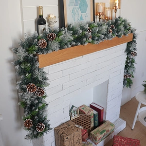 Lush snowy Christmas garland with pine cones draped on a white brick fireplace mantle