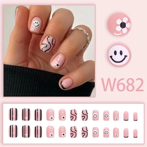 Pink press-on nails with smile faces, white flowers and black wavy lines set
