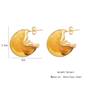 Macro view of C-shaped amber resin earrings with golden stainless steel frame details