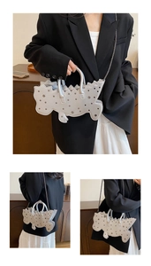 Detailed view of silver dinosaur-shaped bag with metallic rivets and chain strap