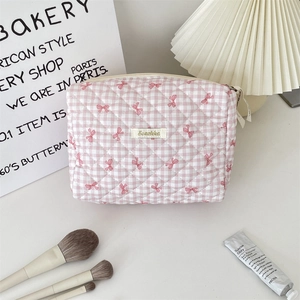 Detailed shot of pink checkered quilted makeup bag with red bows in a cozy setup