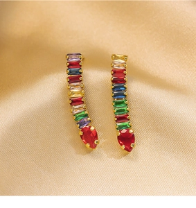 Detailed close-up of gold-plated earrings with multicolor gemstones and red teardrop crystal