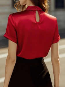 Detail of red satin short sleeve blouse featuring a keyhole back design and silk texture
