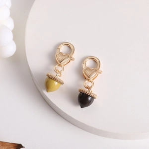 Detail of acorn pendants with gold heart clasps in yellow-green and dark brown finish