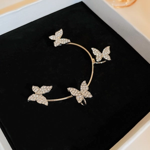 Macro detail of gold butterfly ear cuff featuring sparkling crystals on black velvet