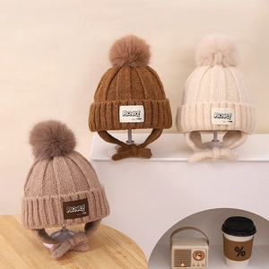 Detailed knit texture of children's winter hats with faux fur pom-poms and ear flaps