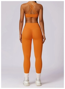 Detail of cross-back yoga bra and high-waist leggings in vibrant orange tech fabric