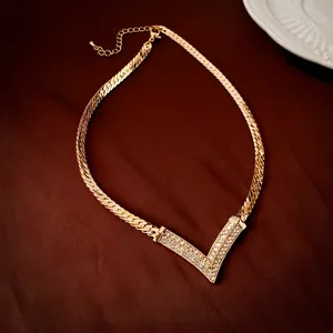 Vintage gold plated V-shaped necklace with rhinestones on a red satin background