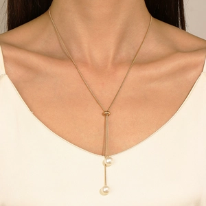 Close-up of golden Y-shaped titanium necklace with adjustable sliding clasp and pearls