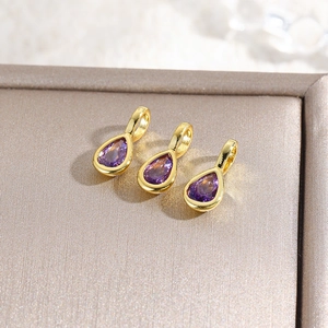 Detailed view of three teardrop pendants with purple zircons and 18k gold plating
