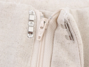Close-up of beige linen trousers featuring a metal hook closure and invisible zipper detail