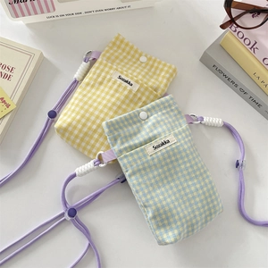Close-up of checkered mini phone pouch with purple woven strap and snap button closure