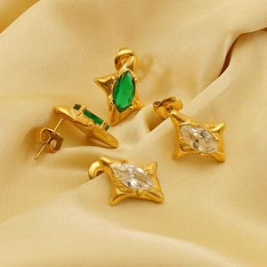 Close-up of star-shaped gold earrings with marquise-cut emerald and clear stones
