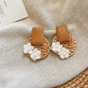 Macro detail of rattan hoop earrings with white fabric flowers and faux pearls