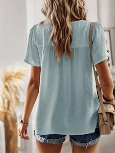 Detail of light blue short-sleeve top featuring dotted texture and a back bow tie