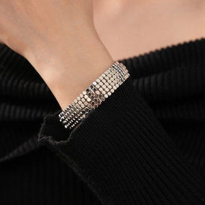 Gros plan d'un bracelet multicouche à disques argentés sur poignet et fond tricoté