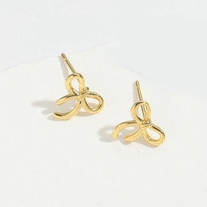 Macro view of polished gold bow earrings showcasing intricate metallic texture