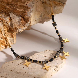 Detailed shot of 18k gold star charms and dark grey natural stones on a delicate chain