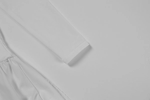 Gros plan d'une manche de robe blanche avec coutures fines et détails de plis doux